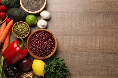 Photo of Different vegetables on wooden table, flat lay and space for text. Vegan diet