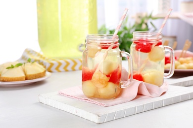 Photo of Mason jars with tasty melon and watermelon ball drink on light table