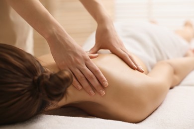 Photo of Woman receiving back massage on couch in spa salon, closeup