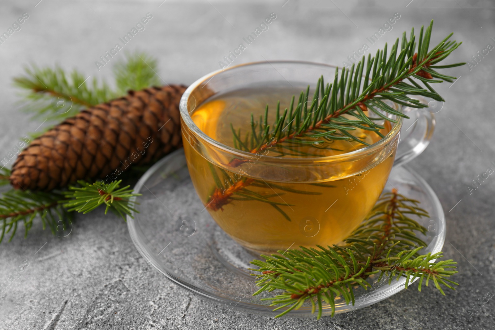 Photo of Cup with delicious immunity boosting tea and fir on grey table, closeup