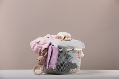 Photo of Laundry basket with baby clothes and toy on white wooden table