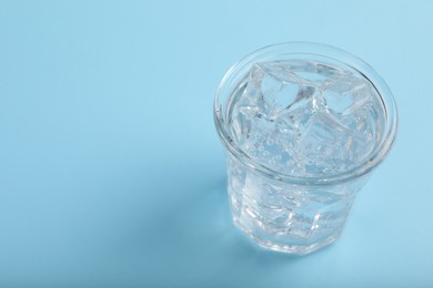 Photo of Glass of soda water with ice on light blue background. Space for text