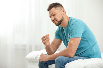 Photo of Emotional man with nicotine patch and cigarette in bedroom