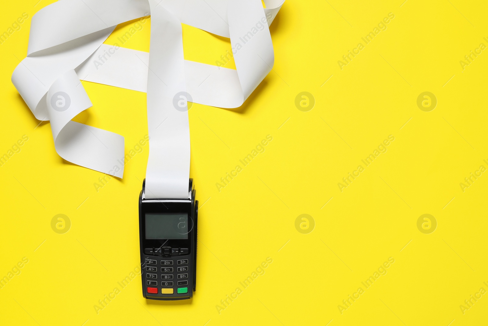 Photo of Payment terminal with thermal paper for receipt on yellow background, top view. Space for text