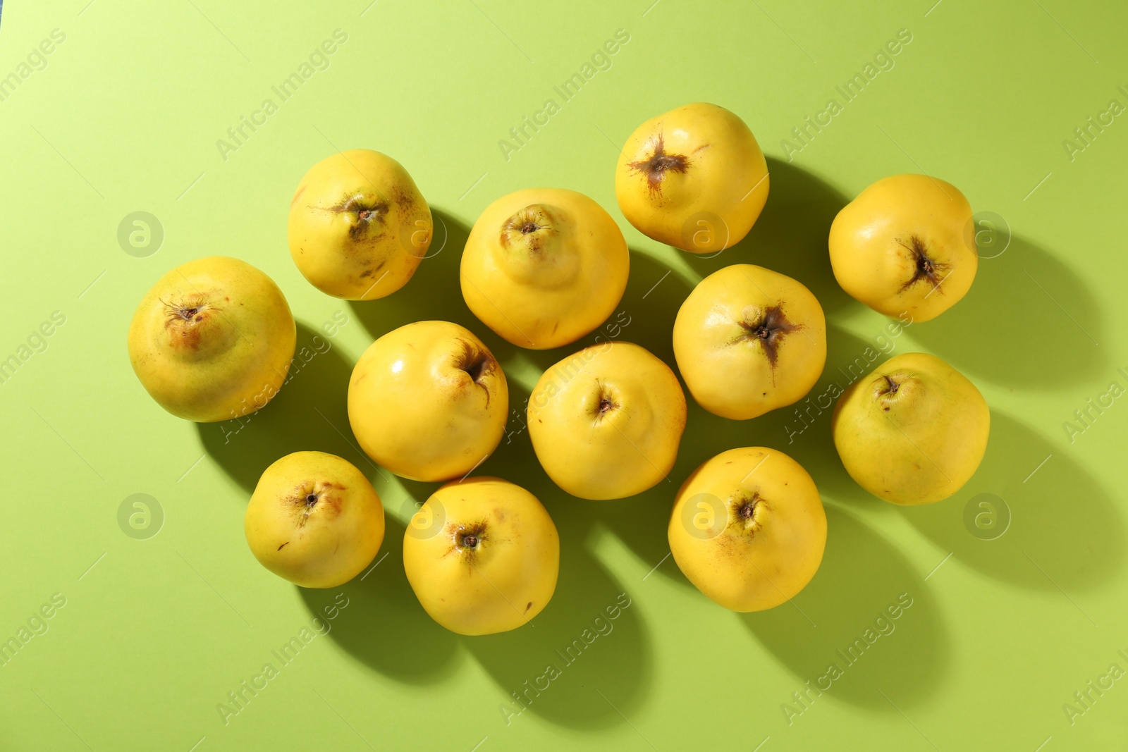 Photo of Tasty ripe quinces on light green background, flat lay