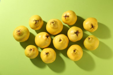 Tasty ripe quinces on light green background, flat lay