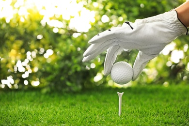 Photo of Player putting golf ball on tee at green course, closeup