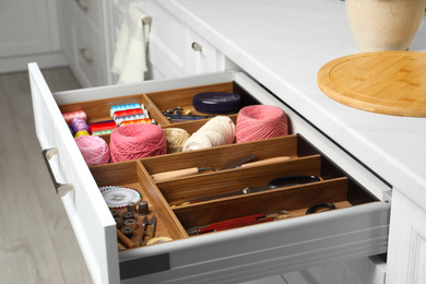 Photo of Sewing accessories in open desk drawer indoors