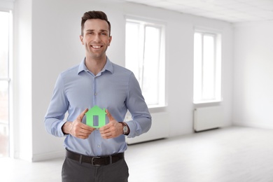 Male real estate agent with house model indoors