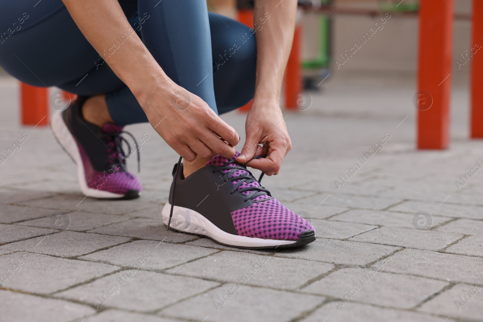 Photo of Woman tying shoelaces before training at outdoor gym, closeup. Space for text