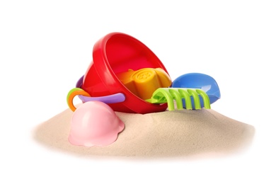 Plastic beach toys on pile of sand, white background