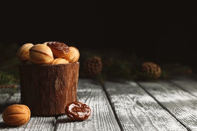 Homemade walnut shaped cookies with boiled condensed milk, fir branches and cones on wooden table, space for text