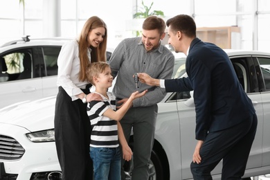 Salesman giving car key to young family in salon