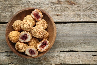 Photo of Delicious sesame balls with red bean paste on wooden table, top view. Space for text