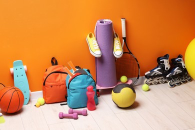 Photo of Many different sports equipment near orange wall indoors