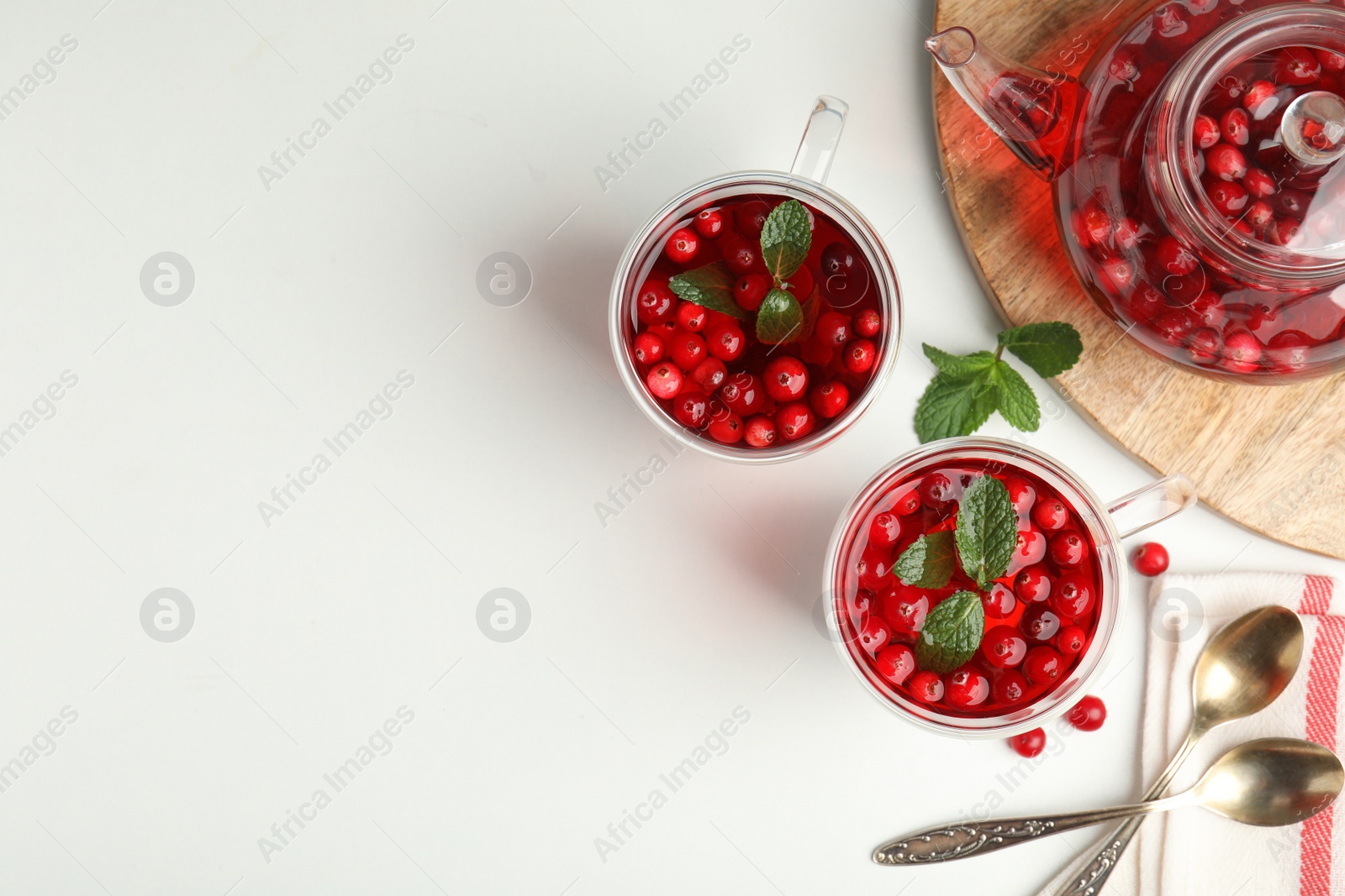 Photo of Tasty hot cranberry tea and fresh ingredients on light table, flat lay. Space for text