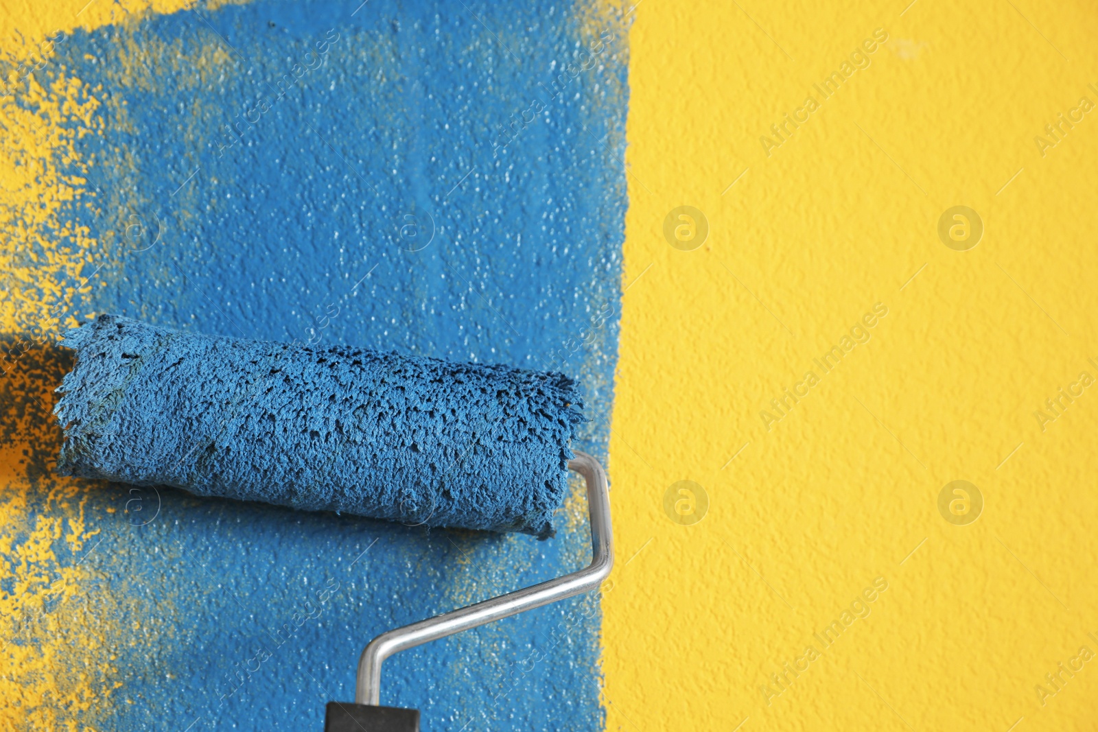 Photo of Painting yellow wall with blue dye, closeup view. Space for text