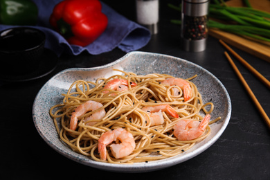 Photo of Tasty buckwheat noodles with shrimps served on black table