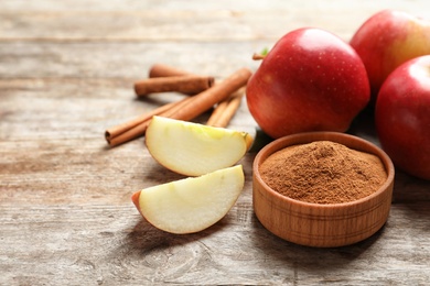 Photo of Fresh apples with cinnamon sticks and powder on wooden table