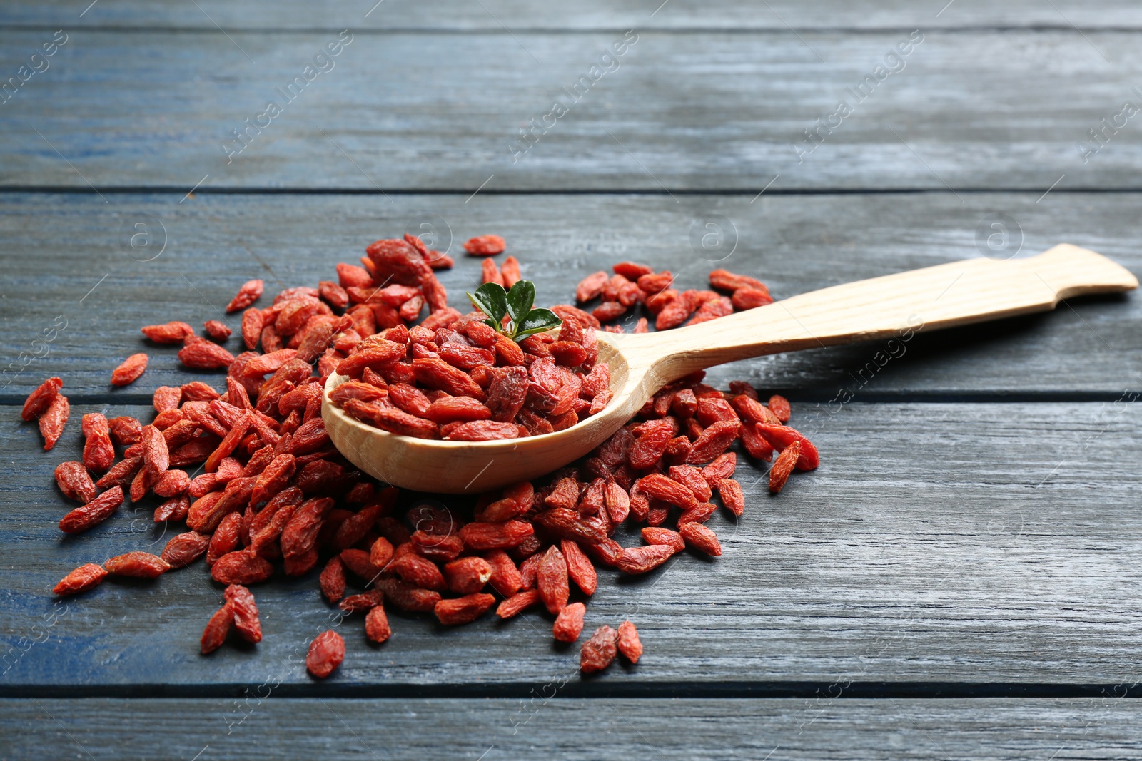 Photo of Spoon and dried goji berries on wooden table. Healthy superfood