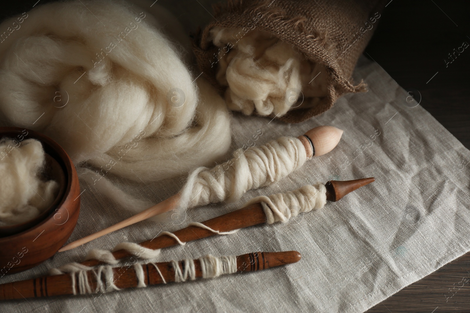 Photo of Soft white wool and spindles on table