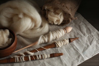 Photo of Soft white wool and spindles on table