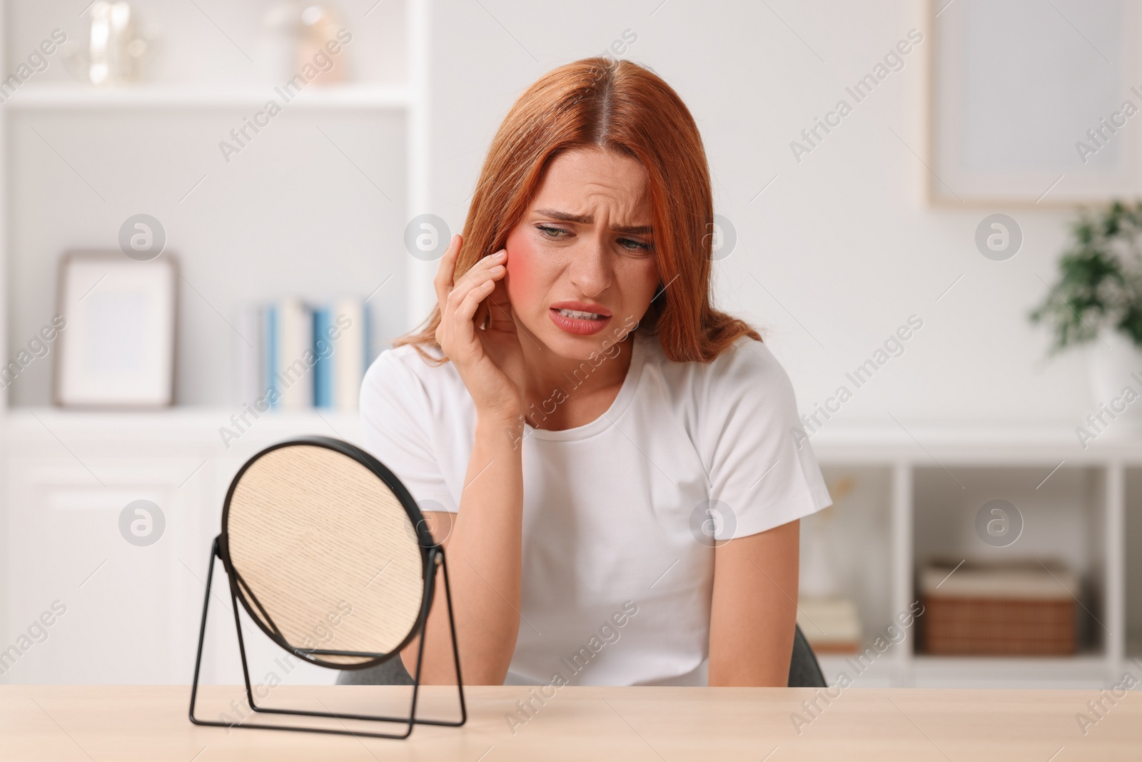 Photo of Suffering from allergy. Young woman with mirror checking her face at home