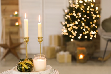 Photo of Burning candles and Christmas gift box on tray indoors. Space for text