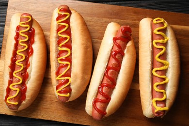 Photo of Delicious hot dogs with mustard and ketchup on wooden table, flat lay