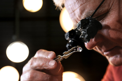 Professional jeweler evaluating beautiful gemstone, closeup view