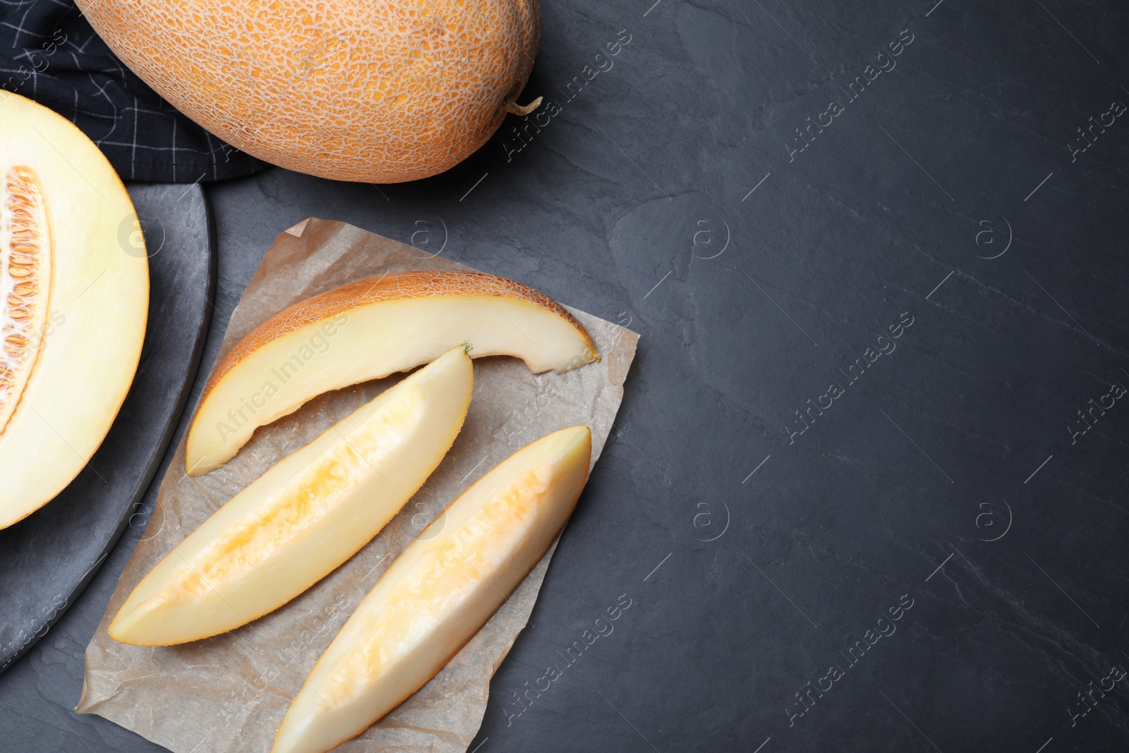 Photo of Slices of delicious honey melon on black table, flat lay. Space for text