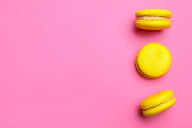 Photo of Delicious yellow macarons on pink background, flat lay. Space for text