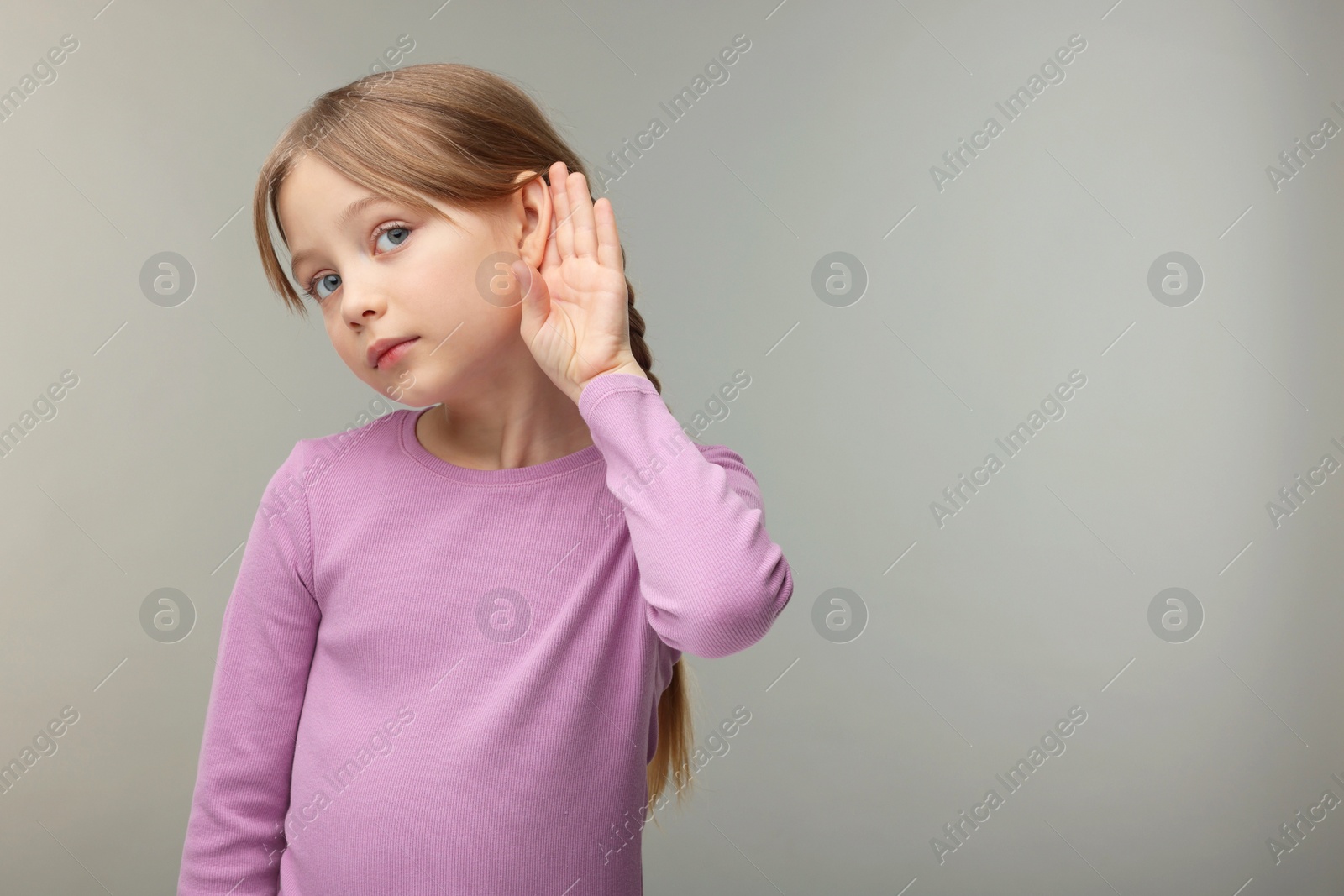 Photo of Little girl with hearing problem on grey background. Space for text