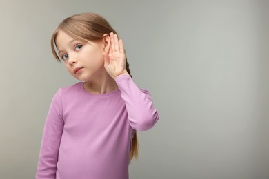 Photo of Little girl with hearing problem on grey background. Space for text