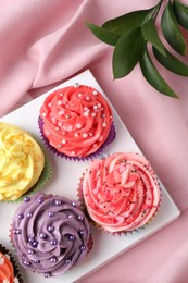 Photo of Delicious cupcake with bright cream on pink fabric, top view