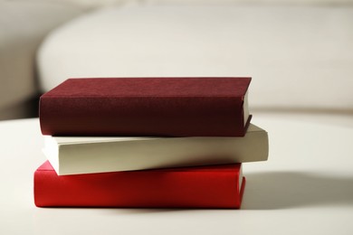 Photo of Many different books stacked on white table indoors