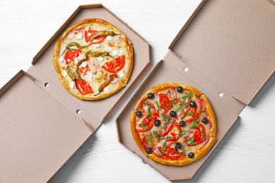 Cardboard boxes with tasty pizzas on wooden background, top view