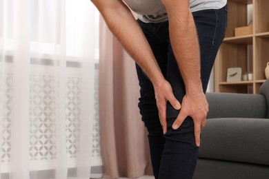 Photo of Man suffering from knee pain indoors, closeup. Space for text