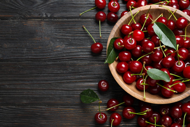 Photo of Delicious ripe sweet cherries on dark wooden table, flat lay. Space for text