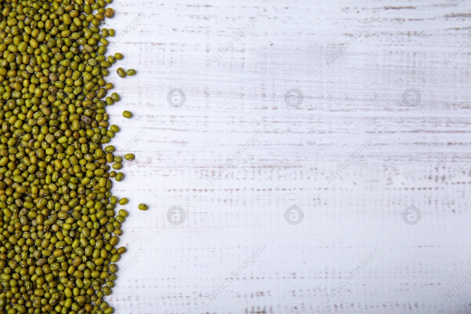 Photo of Green mung beans on white wooden table, top view. Space for text