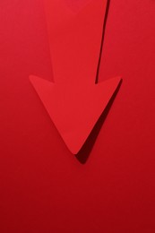Photo of One paper arrow on red background, top view. Space for text
