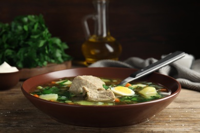 Photo of Delicious sorrel soup with meat and egg served on wooden table