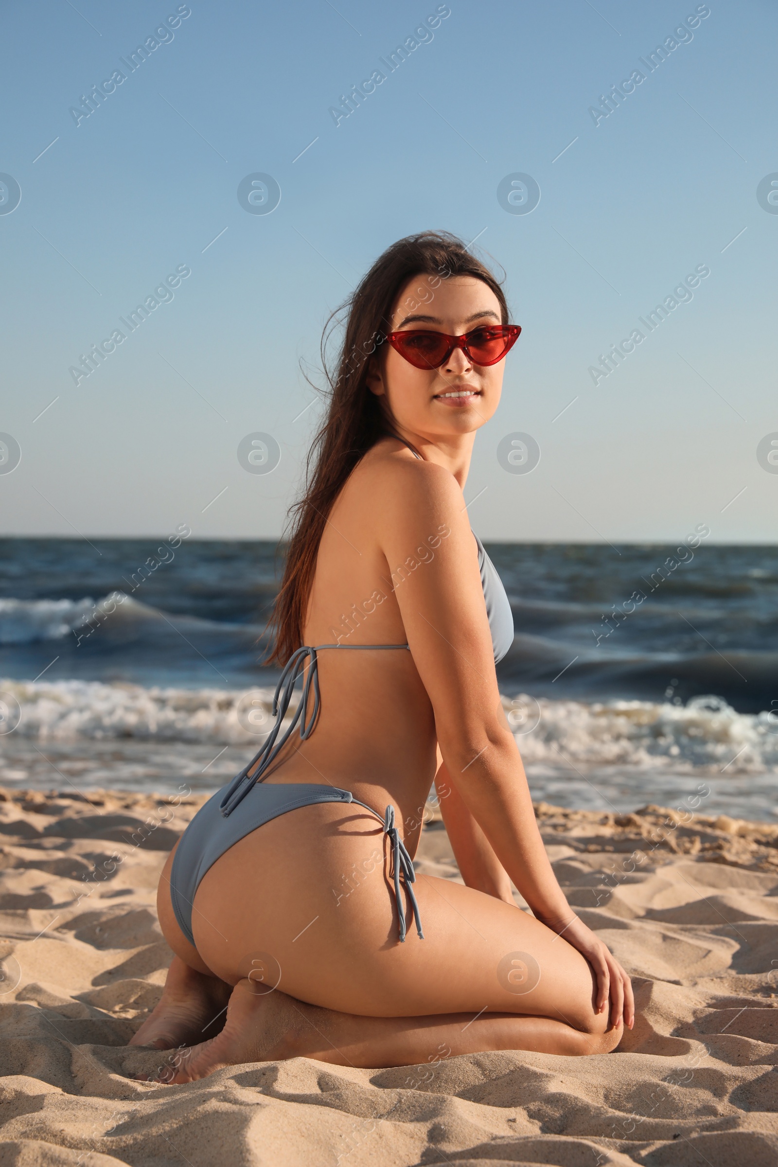 Photo of Beautiful young woman with attractive body posing on beach