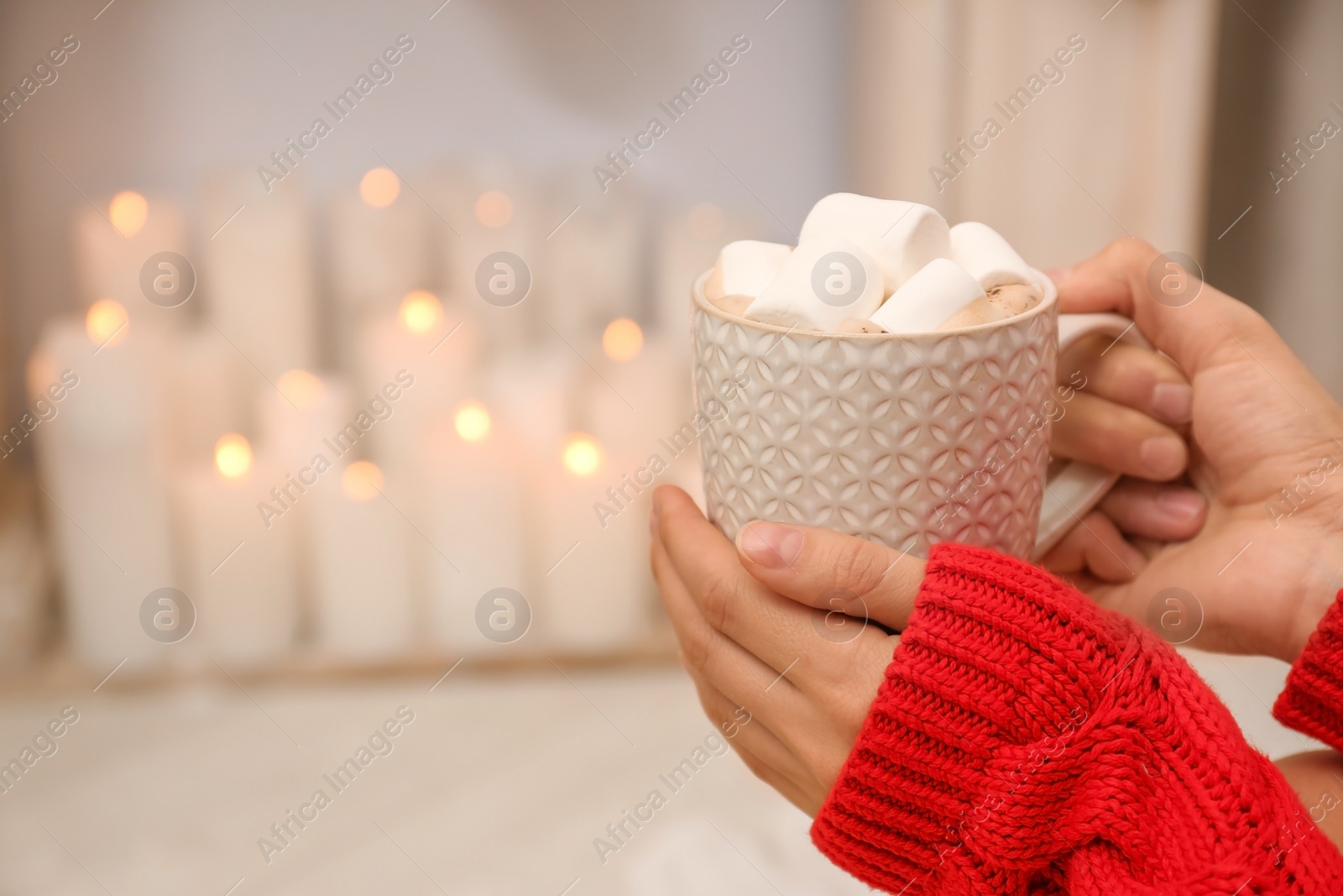 Photo of Young woman with hot drink in living room decorated for Christmas, closeup.