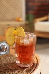 Photo of Glass of tasty cider on wicker table in room. Relax at home