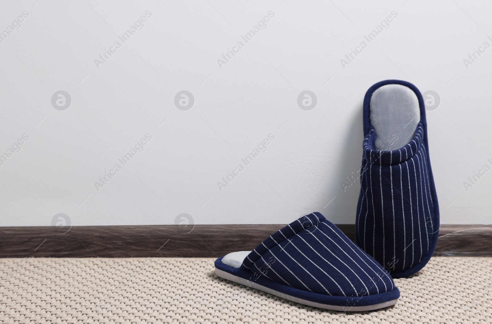 Photo of Pair of stylish slippers on carpet against light grey background, space for text