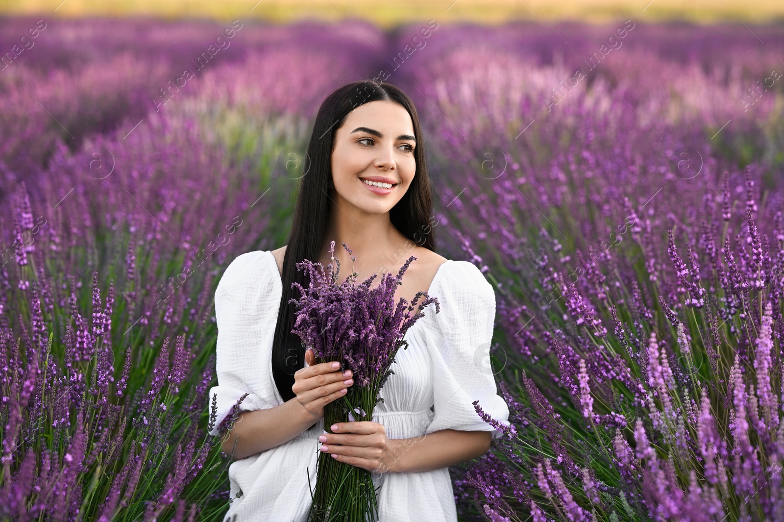 Photo of Beautiful young woman with bouquet in lavender field