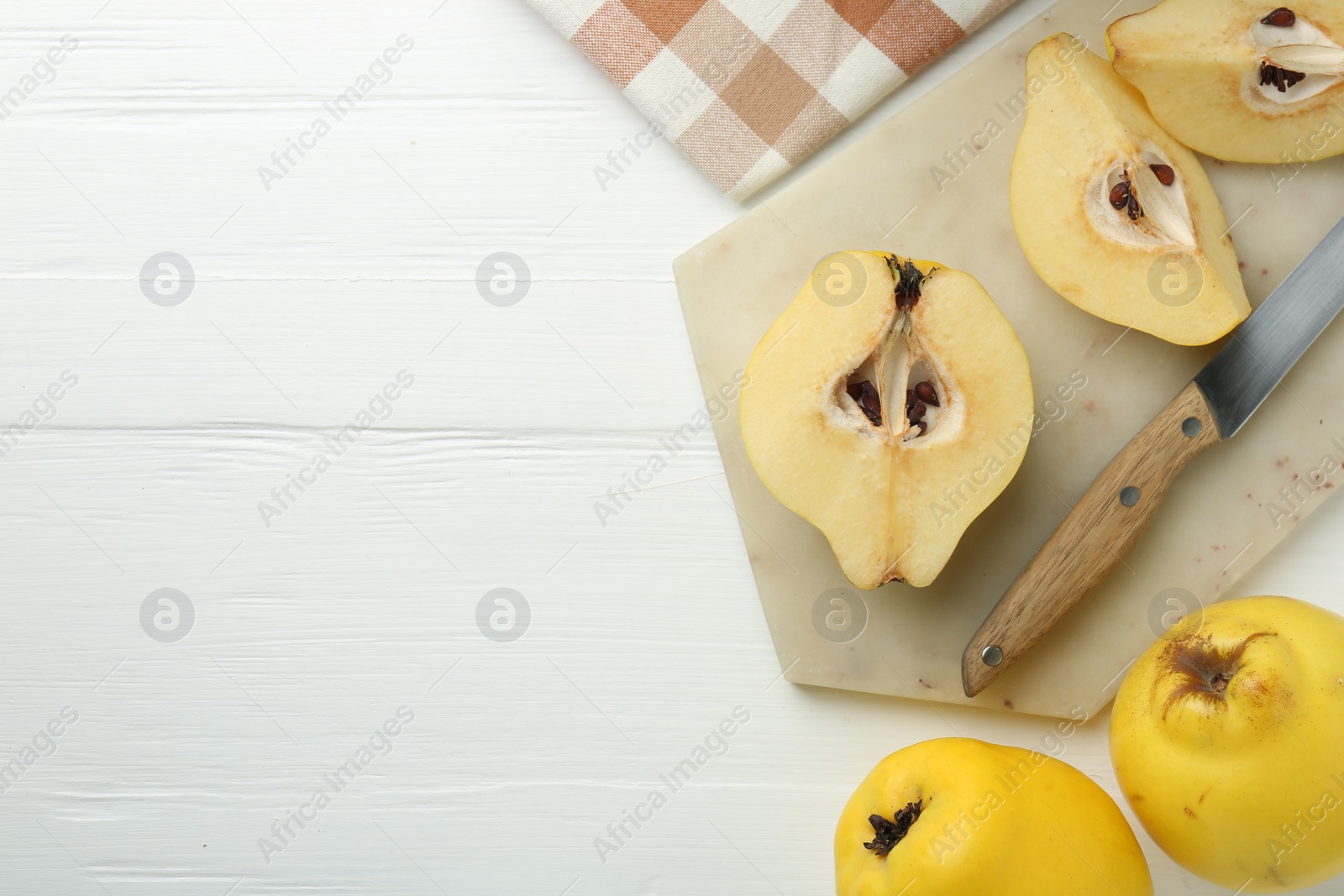 Photo of Tasty ripe quinces and knife on white wooden table, flat lay. Space for text