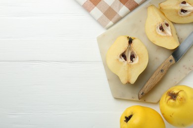 Photo of Tasty ripe quinces and knife on white wooden table, flat lay. Space for text