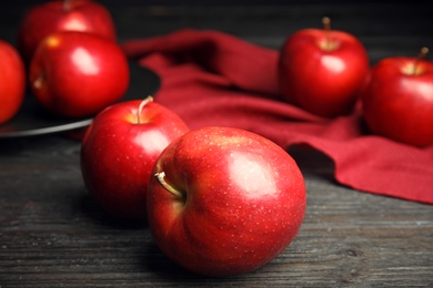 Photo of Ripe juicy red apples on black wooden table